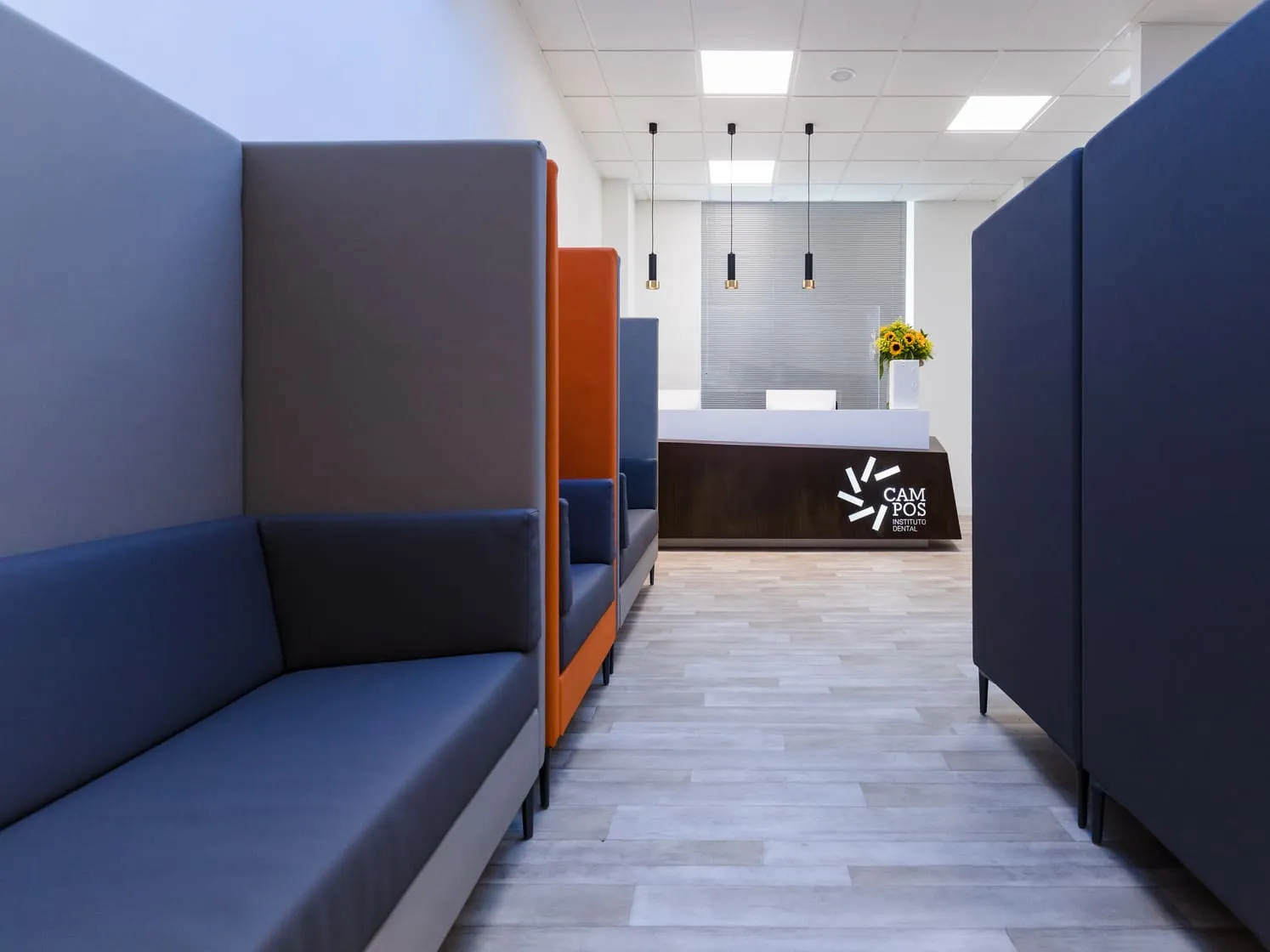 Sala de espera del Instituto Dental Campos en Vigo, con la recepción y el logotipo al fondo