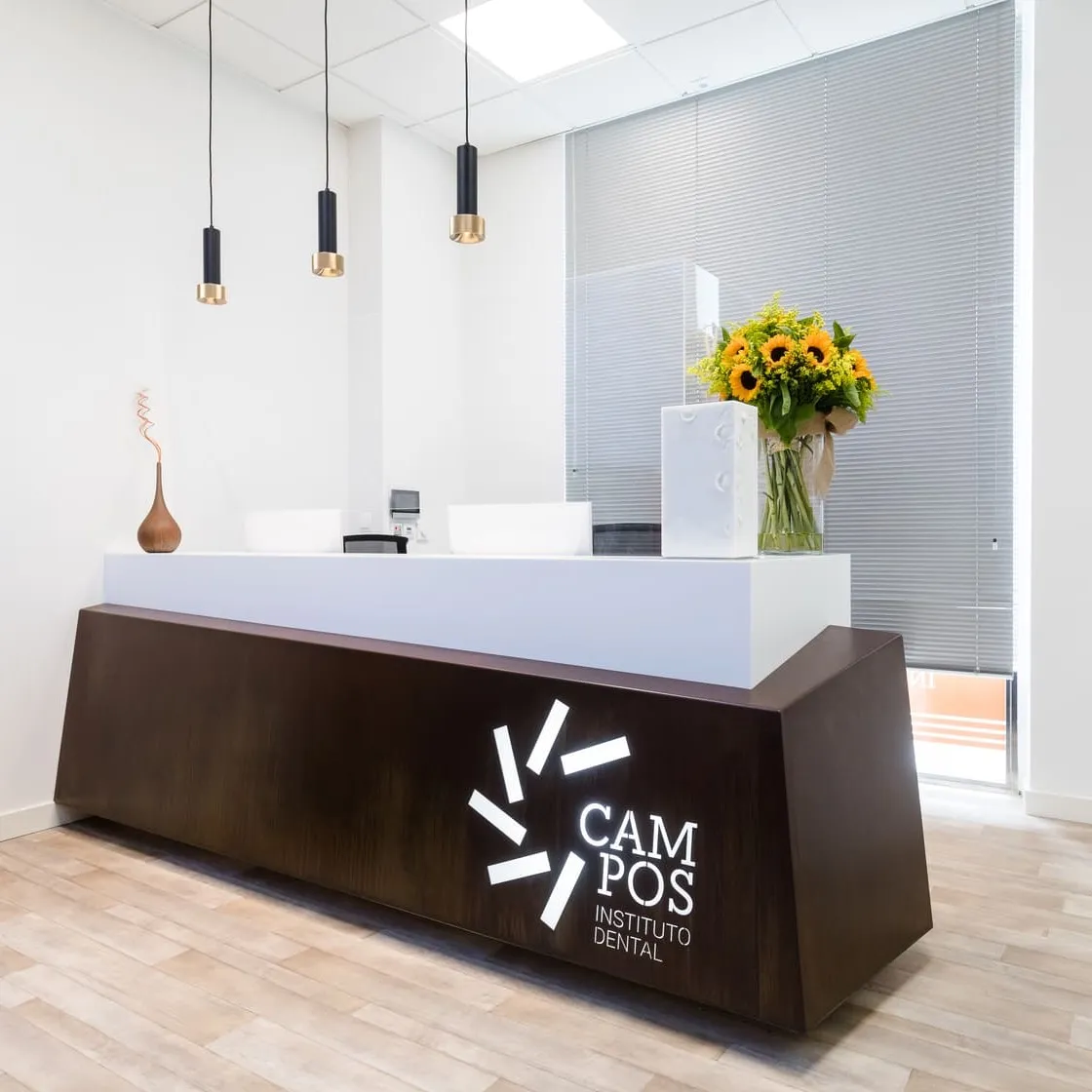 Recepción del Instituto Dental Campos en Vigo, con el logotipo de la marca y un ramo de girasoles